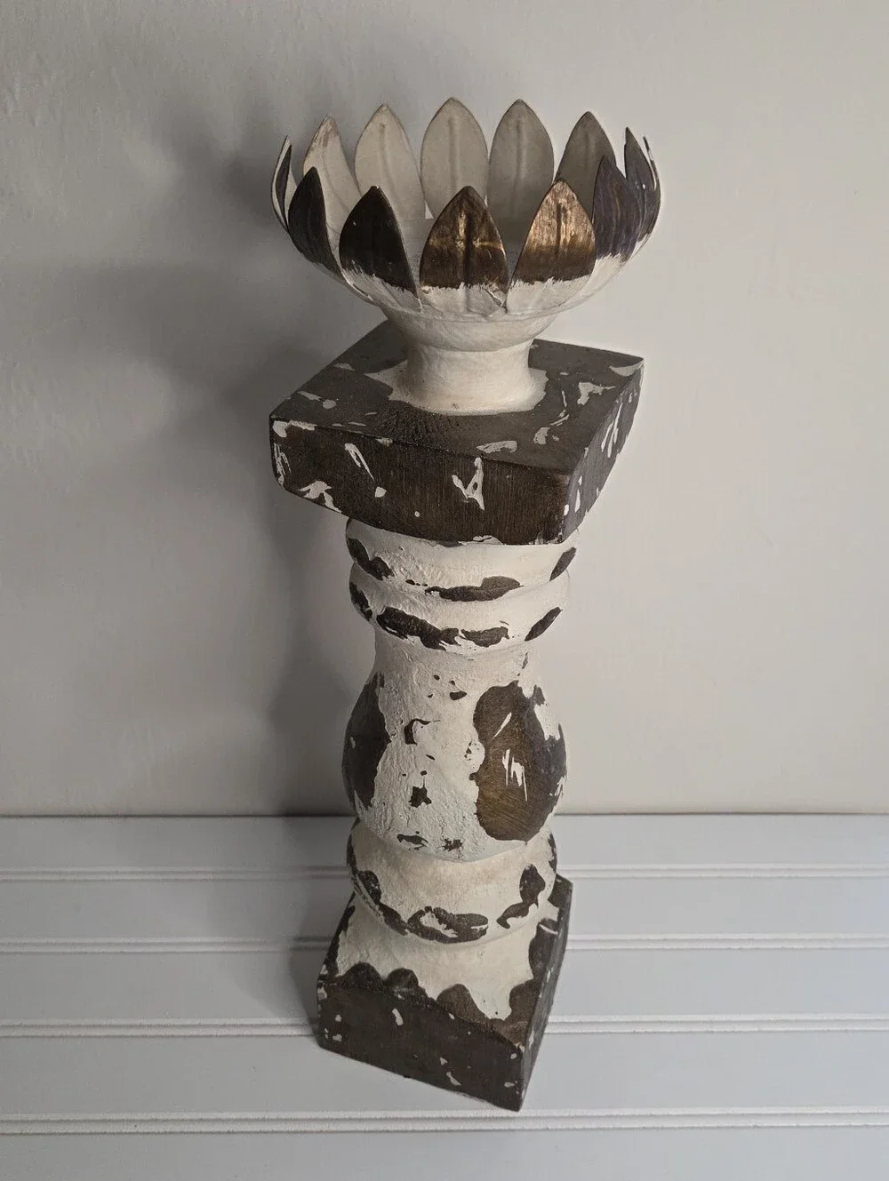 white and gold candlestick features a distressed finish and a lotus-shaped top